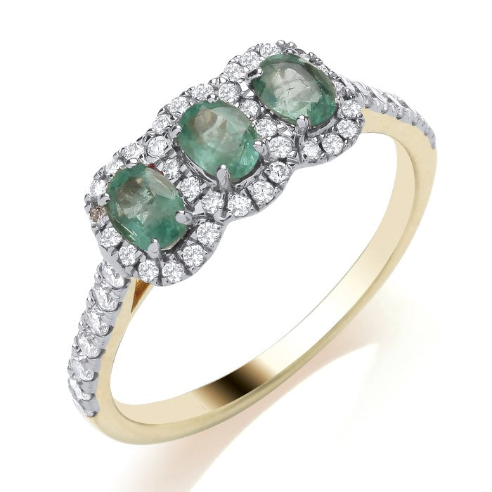 9ct Yellow Gold Emerald and Diamond Trilogy Ring features three oval emeralds in a row, each framed by sparkling diamonds along the setting and diamond-set shoulders.