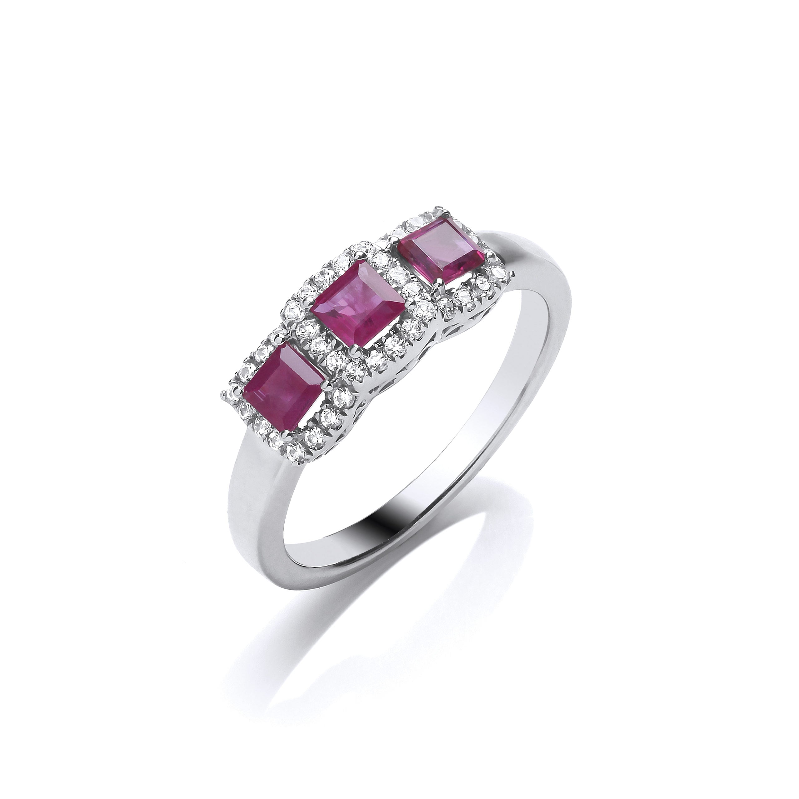 The 9ct Diamond and Ruby Halo Trilogy Ring showcases three princess-cut rubies, each surrounded by sparkling diamonds, set in white gold and displayed on a white background.