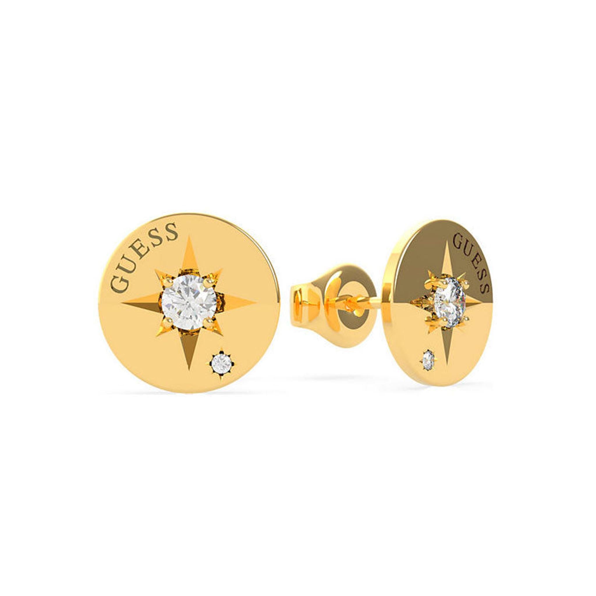 The GUESS WANDERLUST UBE20018 gold tone crystal button stud earrings feature a compass star design with a central clear gemstone, side crystal accents, and "GUESS" engraved on each earring.