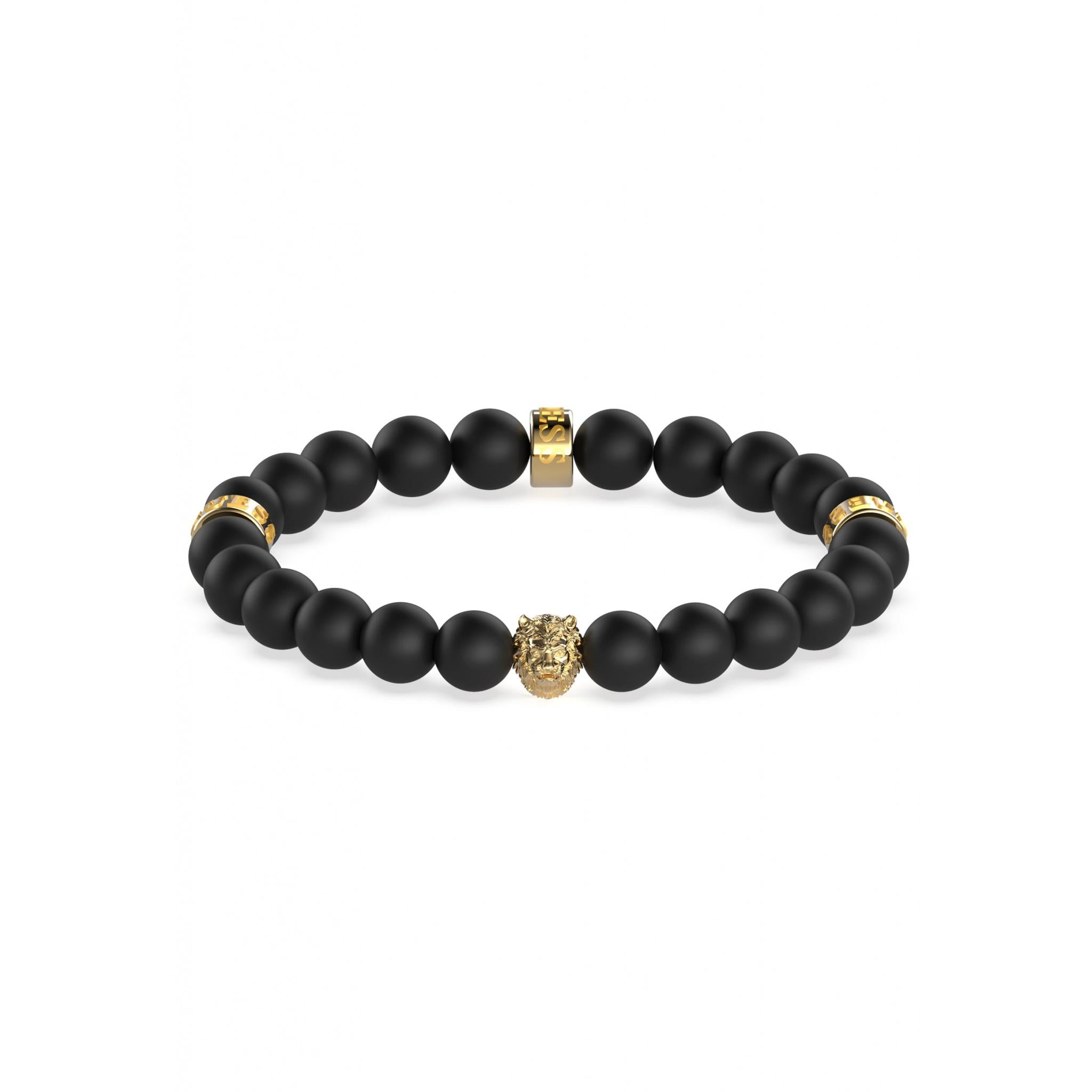 The GUESS JEWELLERY UMB01303YG Gents King Black Bead Bracelet features gold tone stainless steel charms, including a central lion head and three cylindrical spacers. Displayed on white, it's a bold statement for any Guess collection.