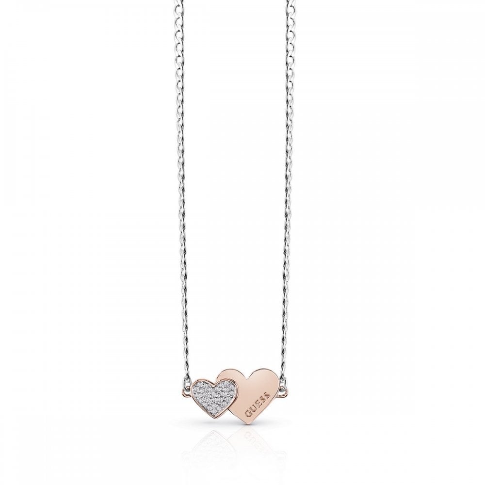 The Guess UBN84076A Me & You Double Heart Necklace features a rhodium-plated silver chain with two heart pendants—one textured, one engraved with "GUESS"—making it a timeless accessory for any look.