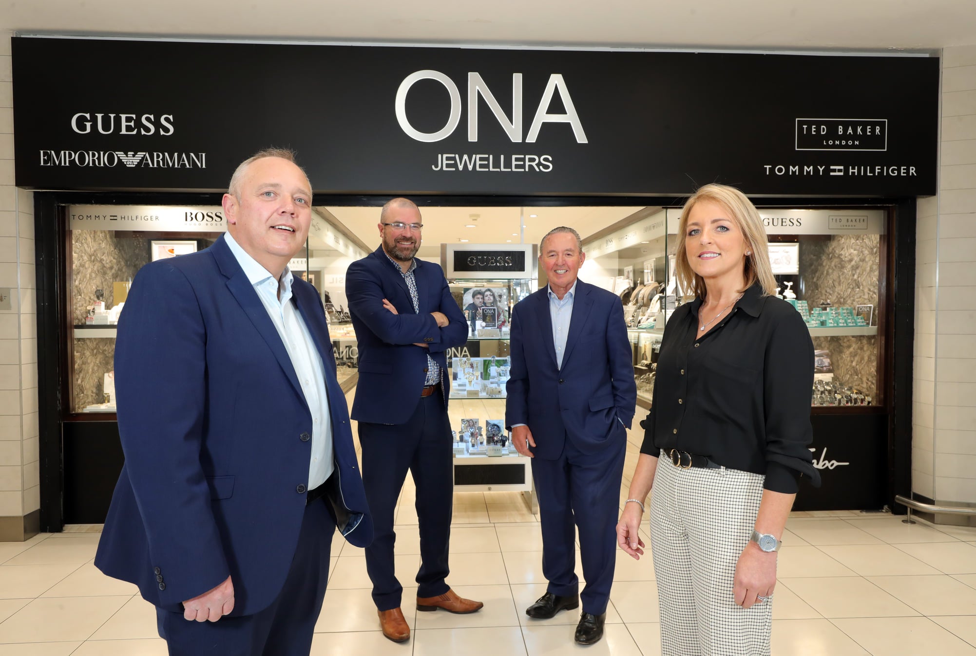 ONA Jewellers team standing outside their store, showcasing luxury jewellery brands including Guess, Emporio Armani, Ted Baker, and Tommy Hilfiger.