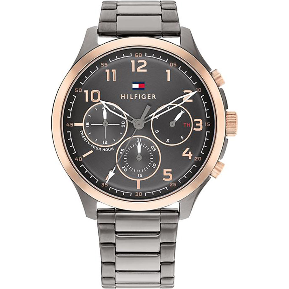 The Tommy Hilfiger Gents Grey Stainless Steel Asher1791871 Watch features a grey stainless steel band, black and gold-tone face with three subdials, plus gold-tone hour markers and hands—a stylish men’s summer watch.