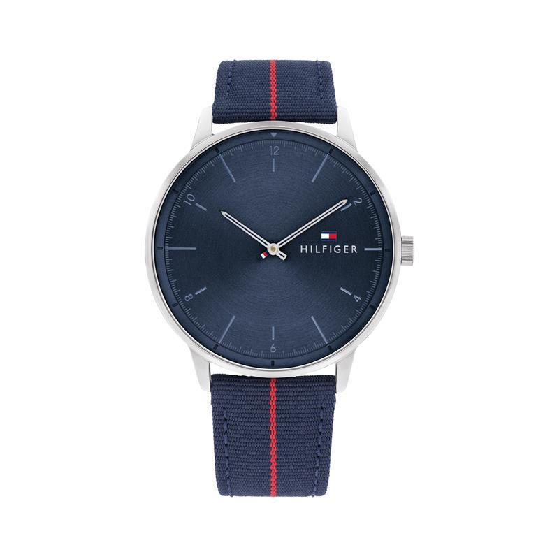 The TOMMY HILFIGER Gents Hendrix Textile Strap Watch 1791844 features a blue dial with silver hour markers, a silver casing, and a blue fabric strap with a red stripe plus the iconic Tommy Hilfiger logo for a sleek, refined style.