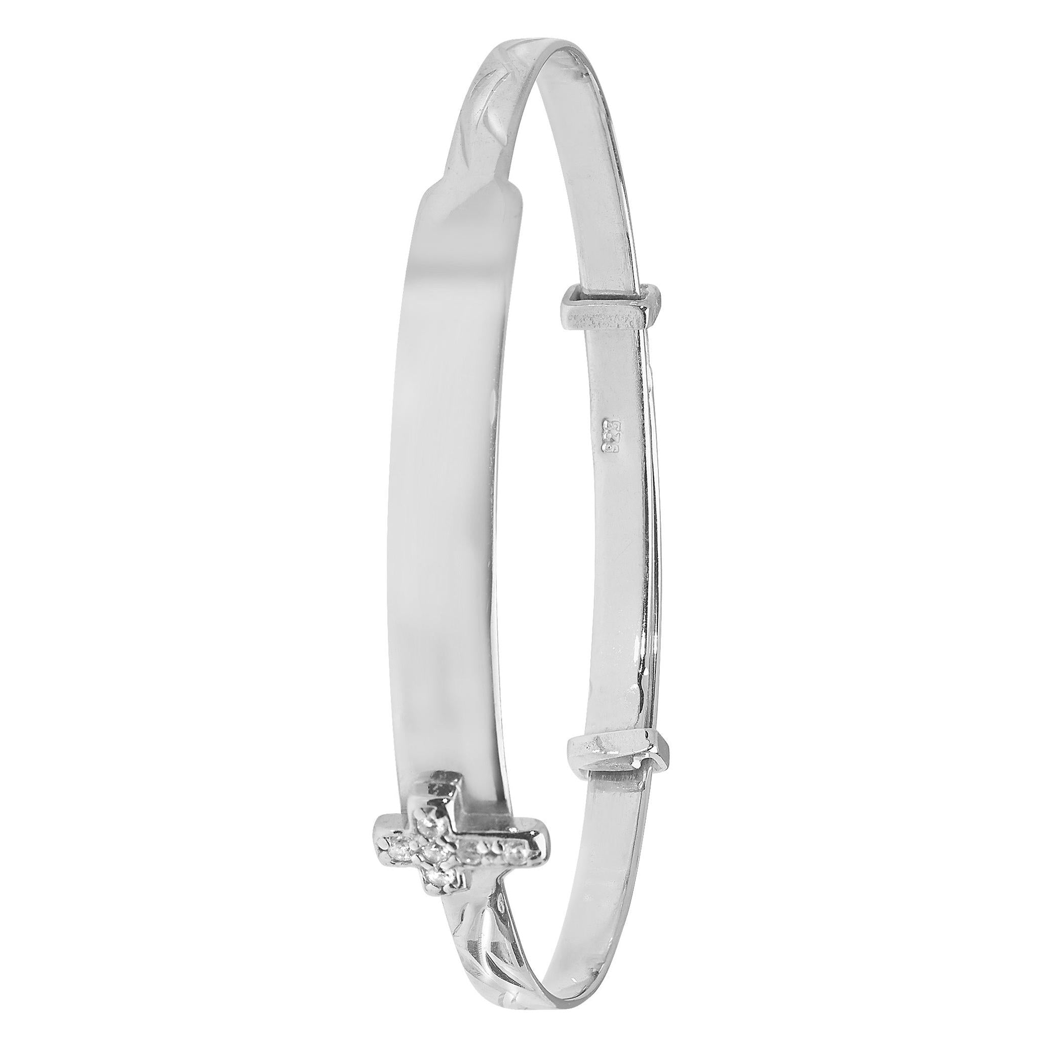 The STERLING SILVER BABY BANGLE ID PLATE WITH CZ CROSS features a plain central plate and a delicate side cross adorned with sparkling CZ stones.