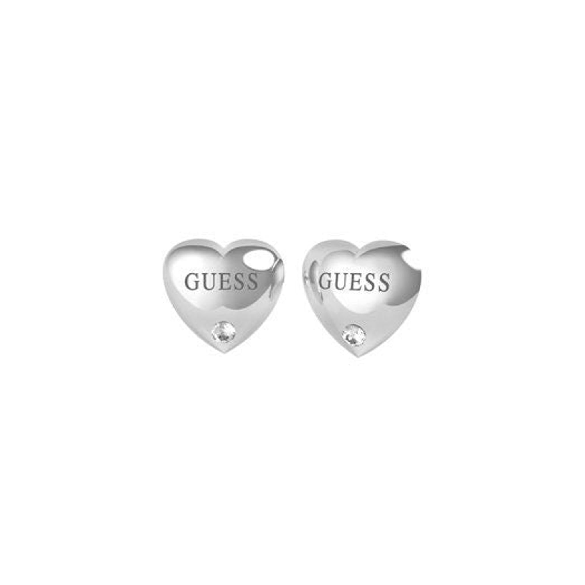 The Jewellery GUESS Is For Lovers SilverTone Heart Earrings UBE70104 feature heart shapes engraved with "GUESS" and are finished with a sparkling clear crystal at the bottom.