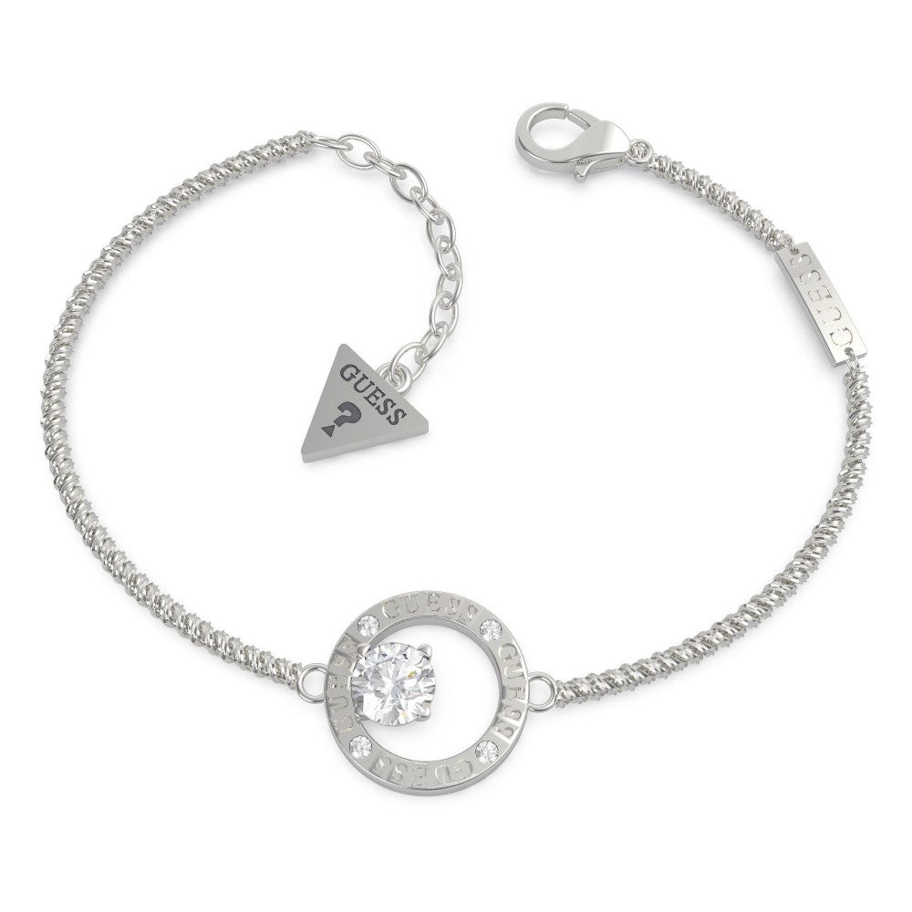 The GUESS JEWELLERY UBB20131-L Silver Tone All Around You Bracelet features a circular pendant with a clear central stone, sparkling crystals, an adjustable chain, and the signature triangular Guess tag.