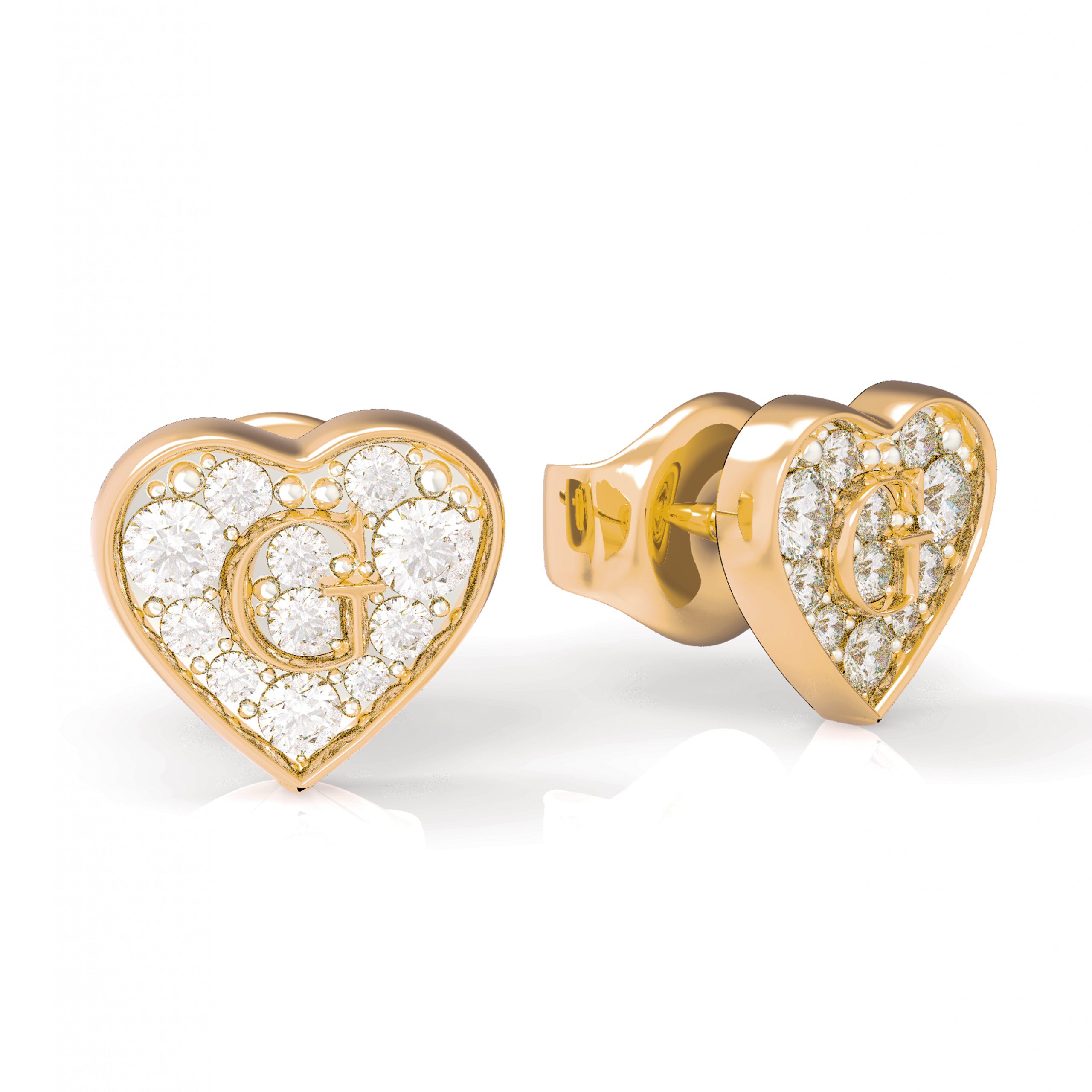 The Guess G-Shine Gold Tone Crystal Earrings (UBE79074) feature gold-plated, heart-shaped studs with clear crystals and the signature Guess G logo at the center of each earring.