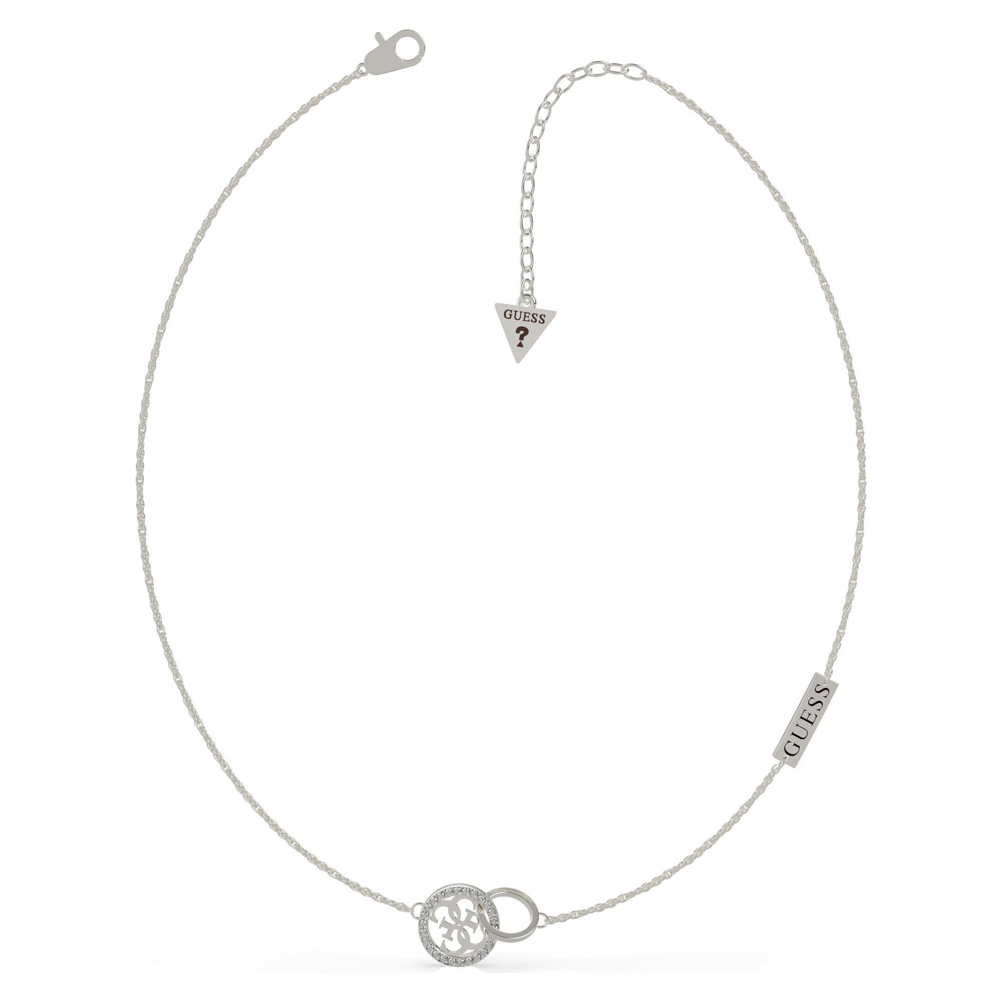 The Guess UBN79045 Women's Silver Tone Equilibre Necklace features a round pendant with a cut-out Guess logo, a rectangular "GUESS" tag, and an adjustable lobster clasp ending in a triangle tag.