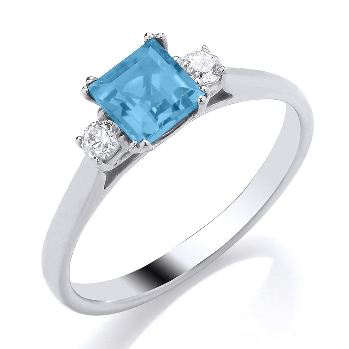 The 9ct White Gold Diamond and Blue Topaz Ring 0.12ct features a square blue topaz center stone accented by two round diamonds, all set in gleaming white gold.