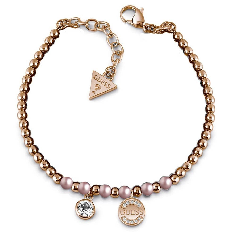 The Guess Rose Gold Plated Swarovski Crystal Bracelet UBB28051-L features rose gold plating, pink Swarovski pearls, a sparkling crystal charm, rhinestone Guess logo charm, and an adjustable clasp with signature triangle tag.