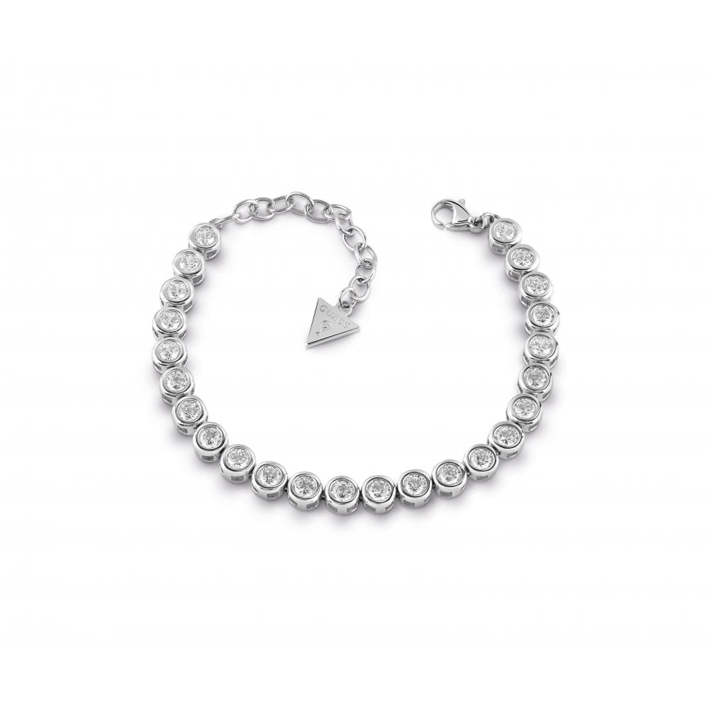 The GUESS Glitter Girl Crystal Tennis Bracelet UBB28126 features rhodium plating, a row of round clear stones, a lobster clasp, and a small triangular Guess tag near the fastening.