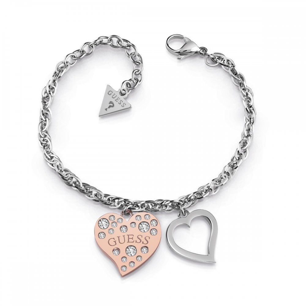 The Guess Silver Twist Chain Bracelet (UBB78095-L) features a rhodium-plated twist chain, lobster clasp, rose gold crystal heart frame charm with "GUESS", silver heart outline, and a small triangular tag.