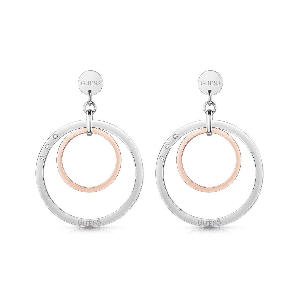 The GUESS JEWELLERY UBE29025 Eternal Circles Earrings feature large silver-tone circles with smaller rose gold-tone centers and sparkling Swarovski crystals, attached to round "GUESS" engraved studs.