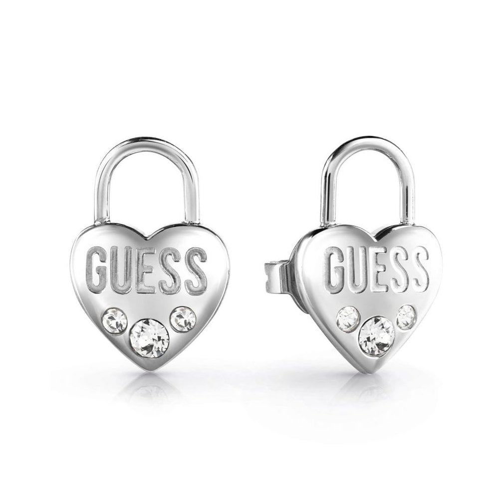 The Guess Jewellery Lock Me Up Silver Tone Heart Padlock Stud Earrings (UBE20054) feature a heart-shaped padlock design with "GUESS" engraved and three clear crystals for added sparkle.