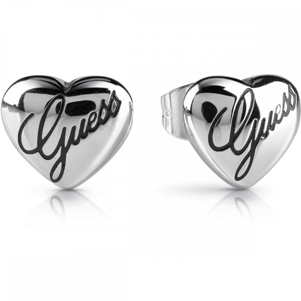 A pair of GUESS Silver Tone Never Without Heart Earrings (UBE28066) featuring shiny, rhodium-plated heart studs with "Guess" written in script.