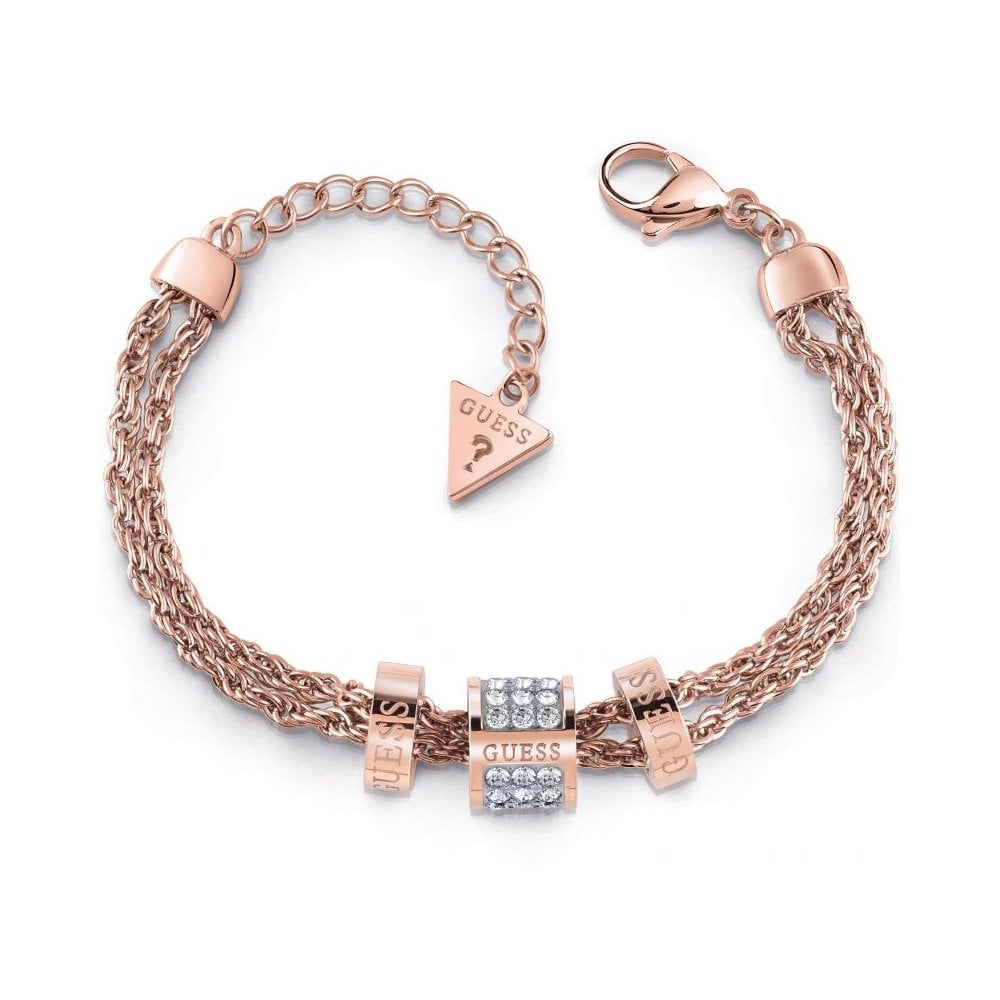 The Guess Jewellery Love Knot Rose Gold Tone With Pave Crystal Double Bracelet (UBB78141-L) features rose gold chains, three GUESS rings, a central pave crystal bead, and a lobster clasp with triangular GUESS tag—an elegant statement piece.
