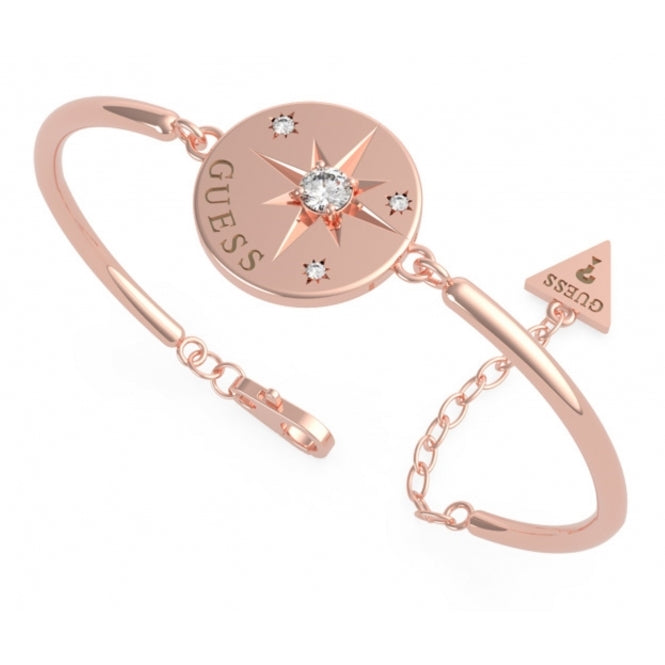 The Guess UBB20026-L Wanderlust ladies rose gold tone bracelet showcases a circular compass coin, four Swarovski crystals, a central gem, and a triangle charm engraved with "GUESS.