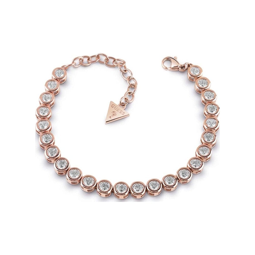 The GUESS UBB28126 Rose Gold Tone Glitter Girl Crystal Tennis Bracelet features round bezel-set Swarovski crystals, a lobster clasp, and an adjustable chain with a triangle Guess logo charm.