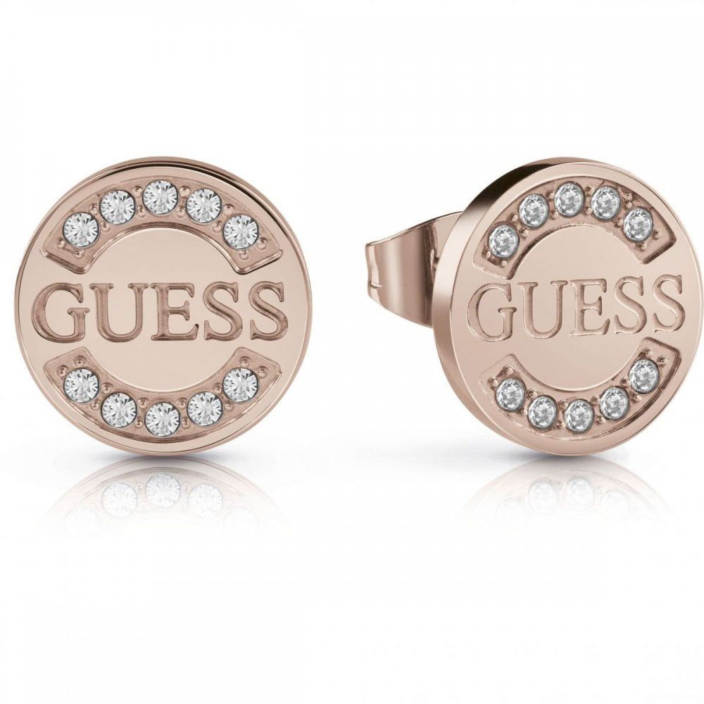 The Guess Uptown Chic Rose Plated Logo Stud Earrings (UBE28030) feature round, rose gold studs with "GUESS" engraving and semi-circles of sparkling Swarovski crystals on each earring.
