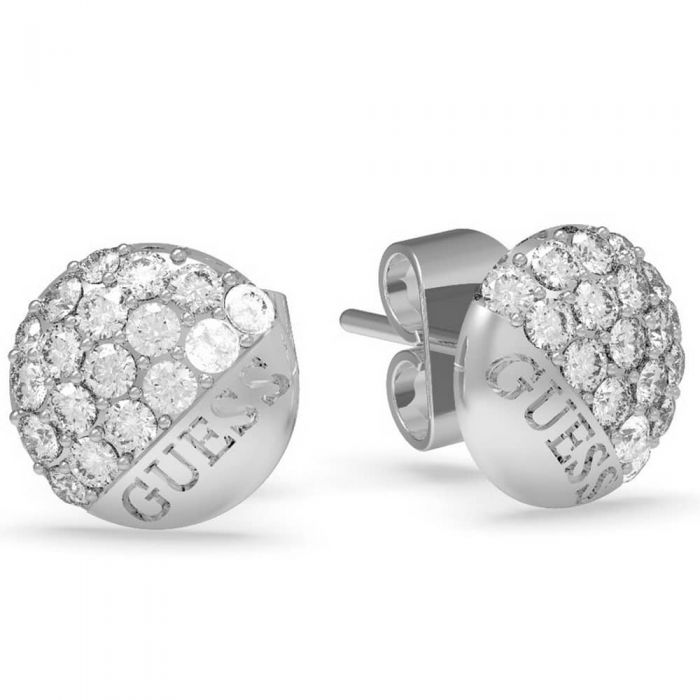 The Guess Embrace Crystal Round Logo Stud Earrings UBE78048 feature round silver studs with clear crystals on half and "GUESS" engraved on the other half, adding sparkle and stylish branding.