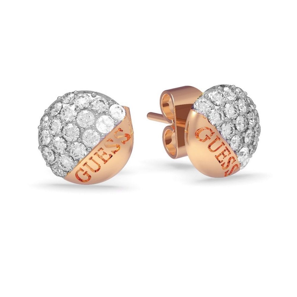 The GUESS JEWELLERY Embrace Crystal Button Earrings UBE78050 are rose gold-tone stainless steel studs, half encrusted with clear crystals and engraved with "GUESS" on the metal.