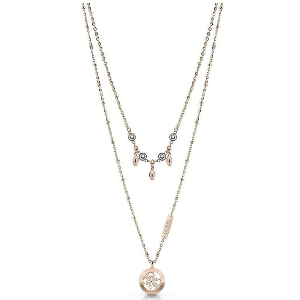 The Guess Ladies Tropical Sun Necklace UBN78020 features a gold double-layered design with a round pendant on the longer chain and small dangling charms with Swarovski crystals on the shorter chain.
