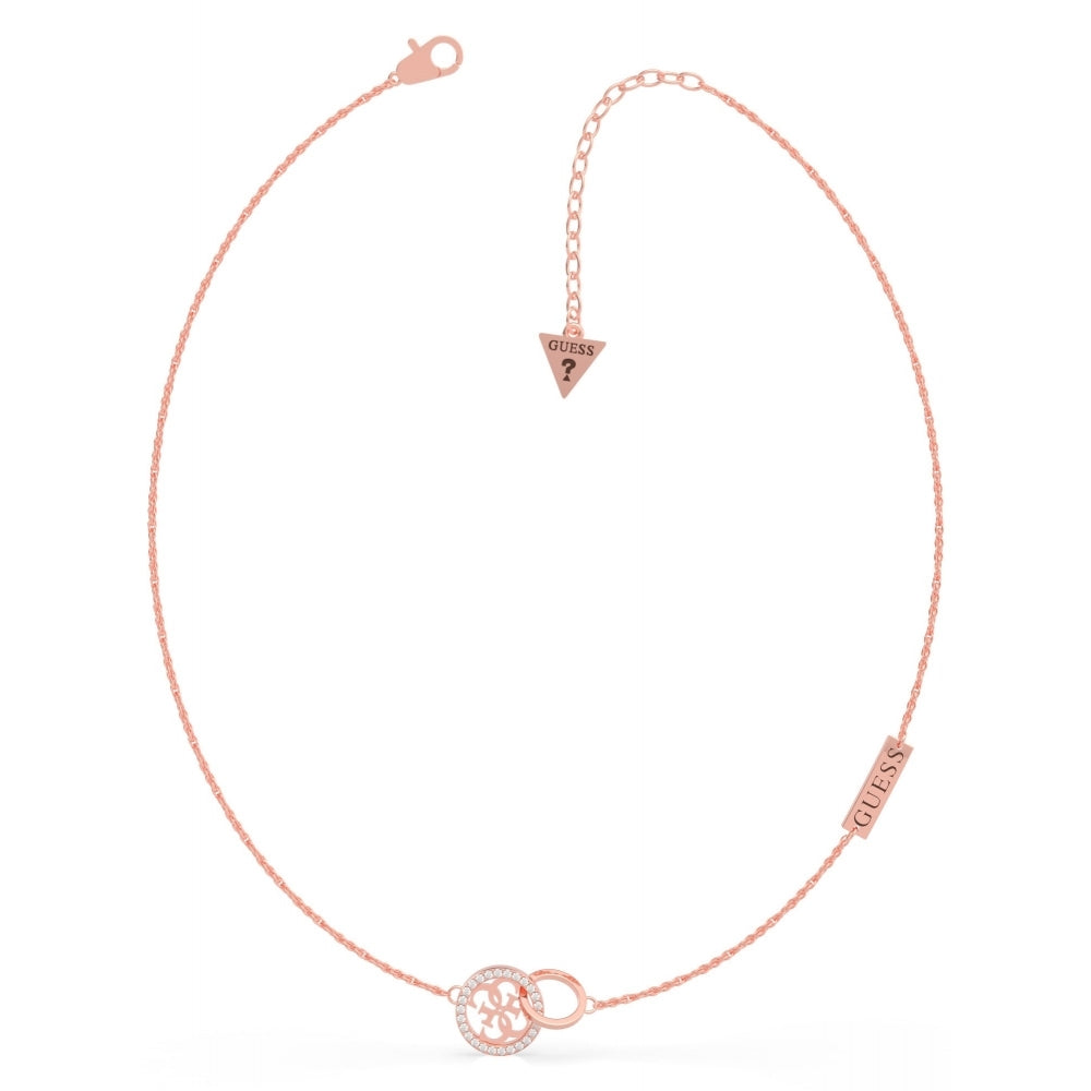 The Guess UBN79046 Women's Rose Gold Tone Equilibre Necklace features a rose gold plated chain with a circular pendant embellished with Swarovski crystals, "Guess" logo plate, and an adjustable clasp with a triangle "Guess" tag.