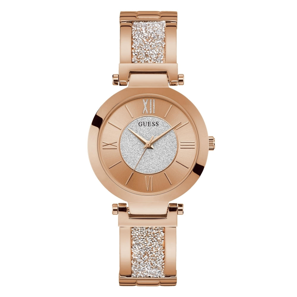 The Guess W1288L3 Women's Aurora Rose Gold Tone Watch features a round face with Roman numerals, a glittery silver dial, and a band accented by two sections of sparkling Swarovski crystals.