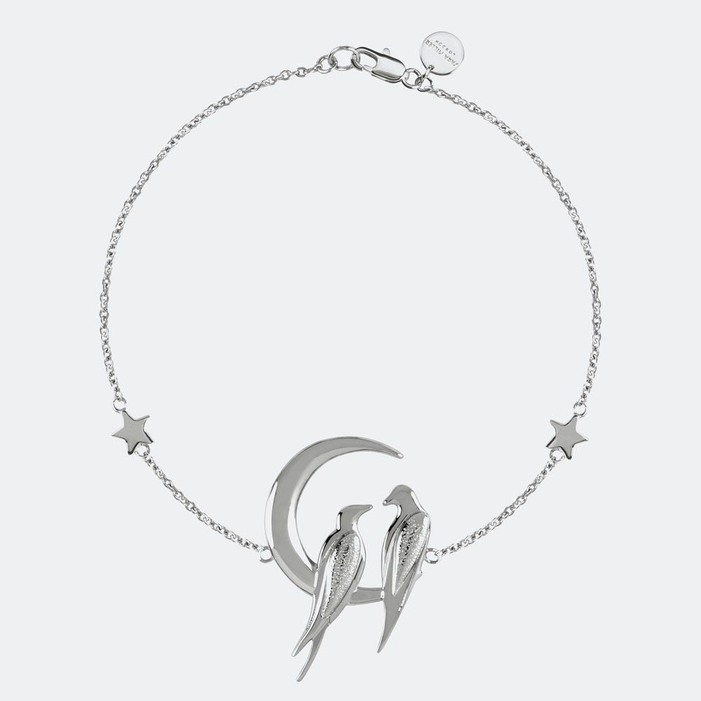 The Sara Millar Love Bird Bracelet (SAJ3001) features two silver birds on a crescent moon with star charms, showcasing elegant jewellery against a plain background.