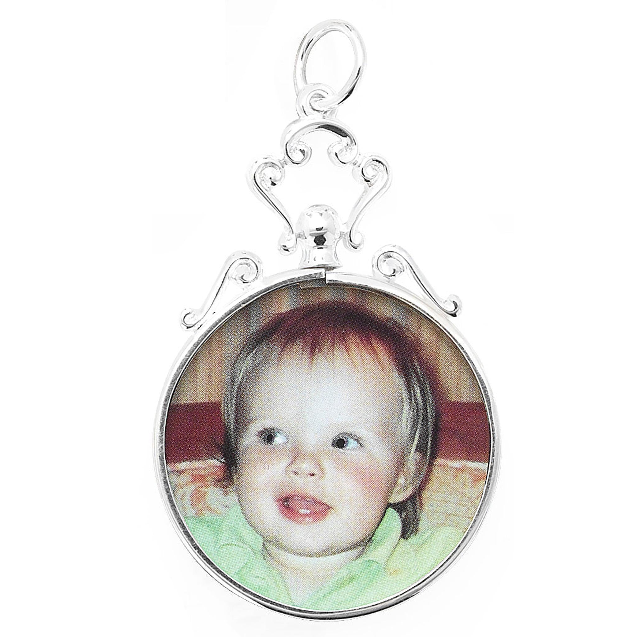 The STERLING SILVER SMALL ROUND PICTURE PENDANT WITH SCROLL TOP is a 27mm silver pendant featuring a photo of a smiling toddler in a green shirt against a neutral background.