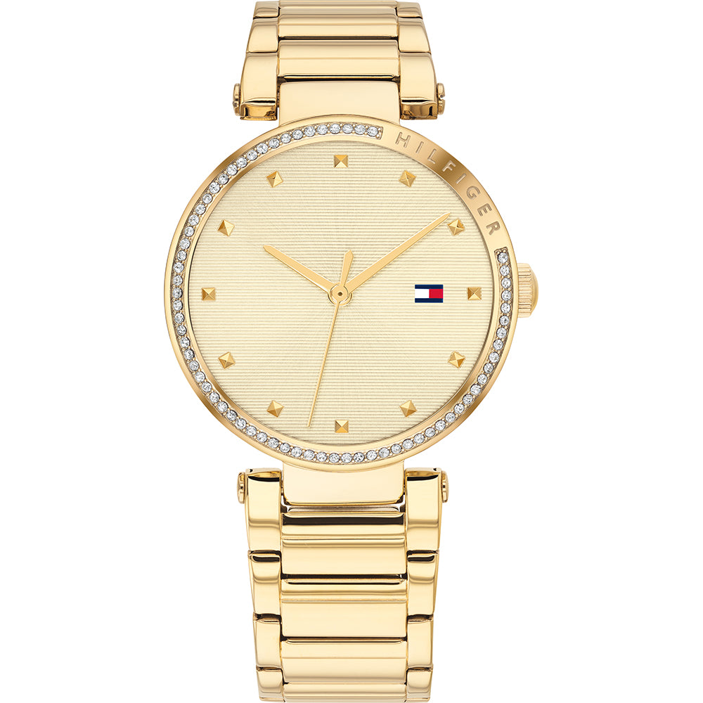 The Tommy Hilfiger 1782235 Lynn watch features a gold-tone round face, crystal accents, minimalist hour markers, and the signature logo at 3 o’clock.