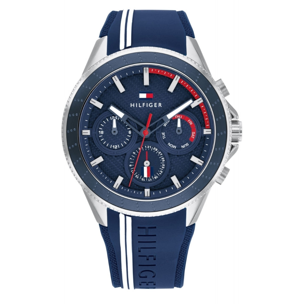 The Tommy Hilfiger 1791859 Men's Aiden watch features a blue silicone strap, textured dial with three subdials, red and white accents, and the brand name on its water-resistant band.