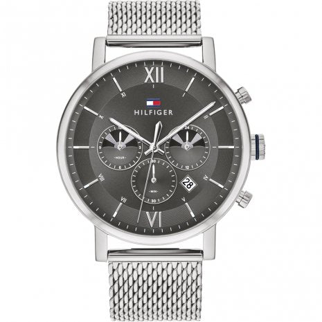 The Tommy Hilfiger 1710396 Watch Evan features a silver chronograph design with a grey dial, three subdials, date display, and a metal mesh strap.