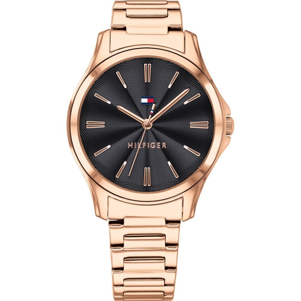 The Tommy Hilfiger 1781951 Lori Ladies Rose Gold Tone Watch features a black textured dial, minimalist hour markers, and the Tommy Hilfiger logo displayed beneath the 12 o'clock position.